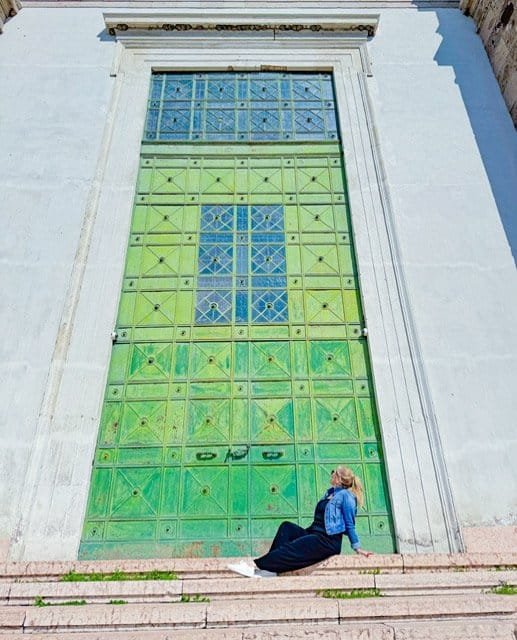 Charity seated at the base of the towering green bronze door of the Cathedral of Esztergom, Hungary