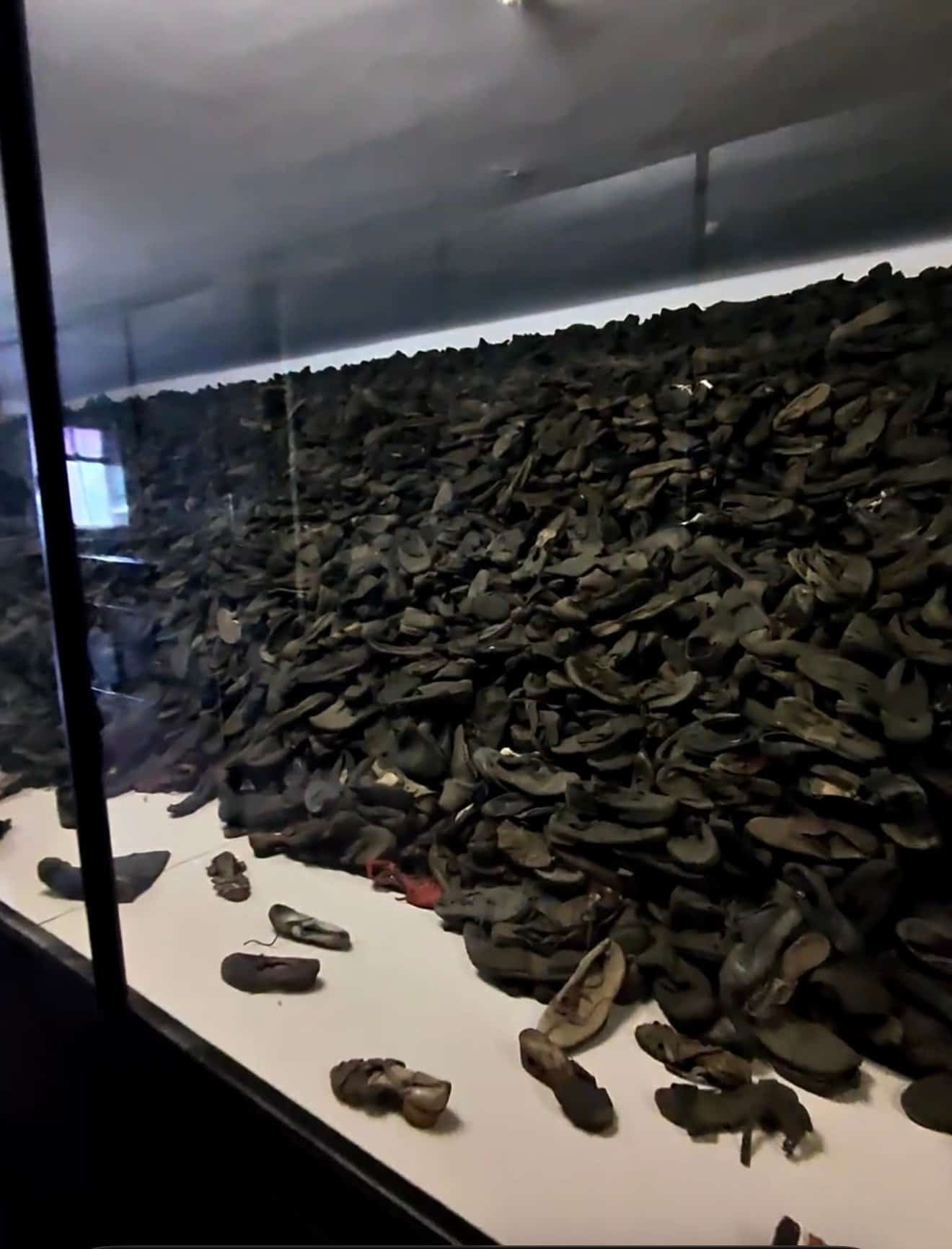 The wall of shoes confiscated from prisoners at Auschwitz, displayed behind glass at the memorial museum