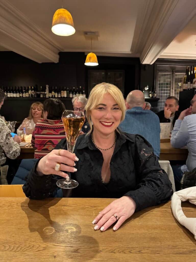 Charity raising a glass of sparkling wine at a candlelit wine bar in Strasbourg