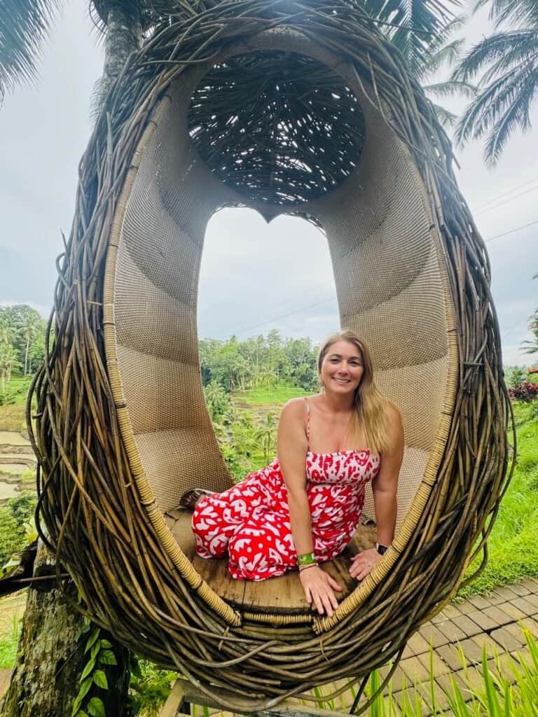 Charity seated in a woven bird's nest swing overlooking the rice terraces of Ubud, Bali