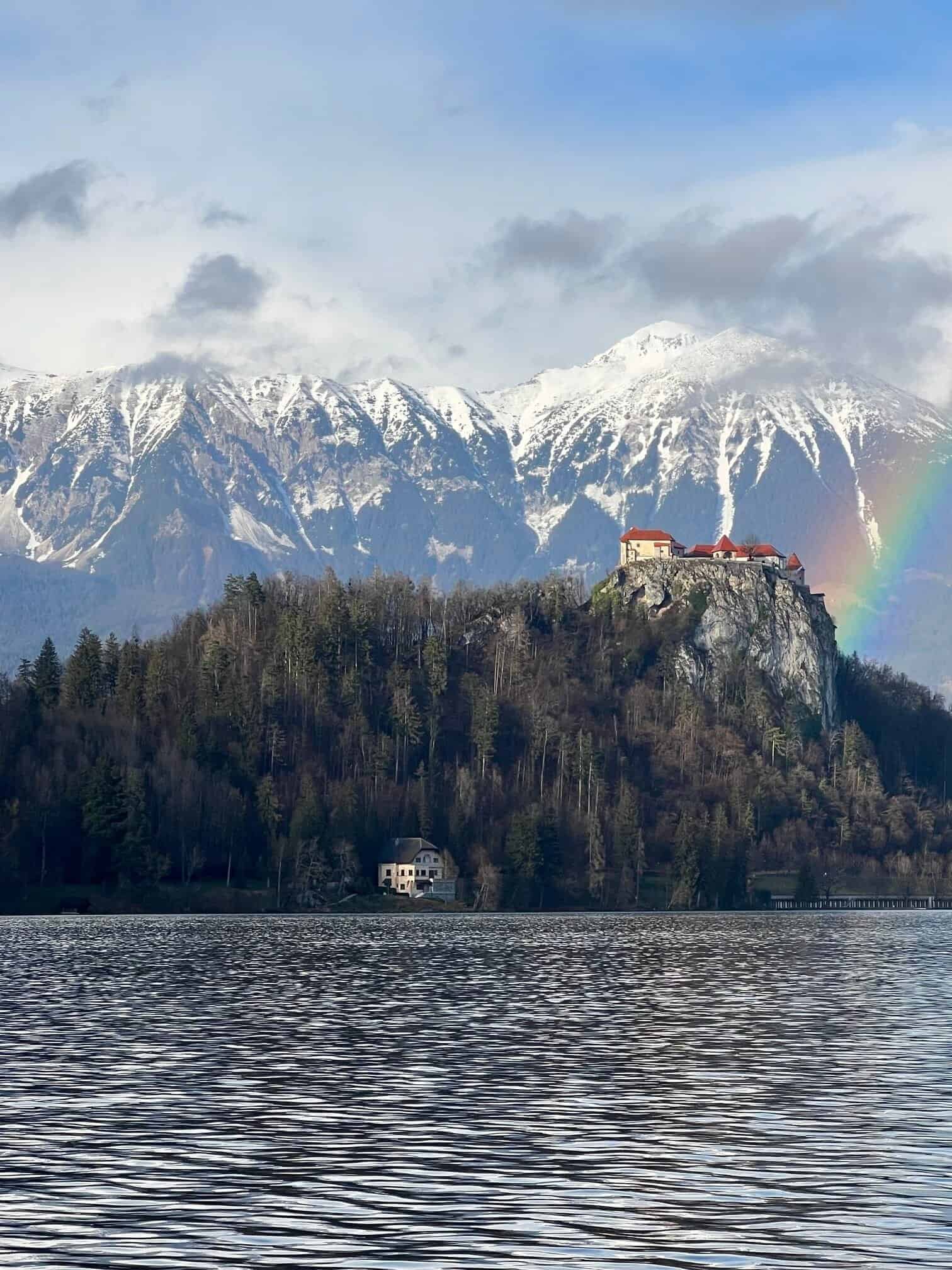 Lake Bled in Slovenia with snow-capped alpine mountains and a partial rainbow