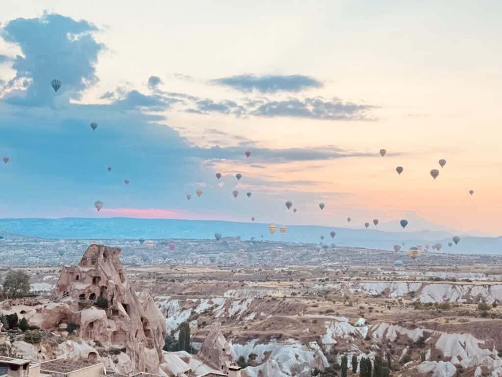 Hot air balloons drifting over the rock formations of Cappadocia, Turkey at sunrise