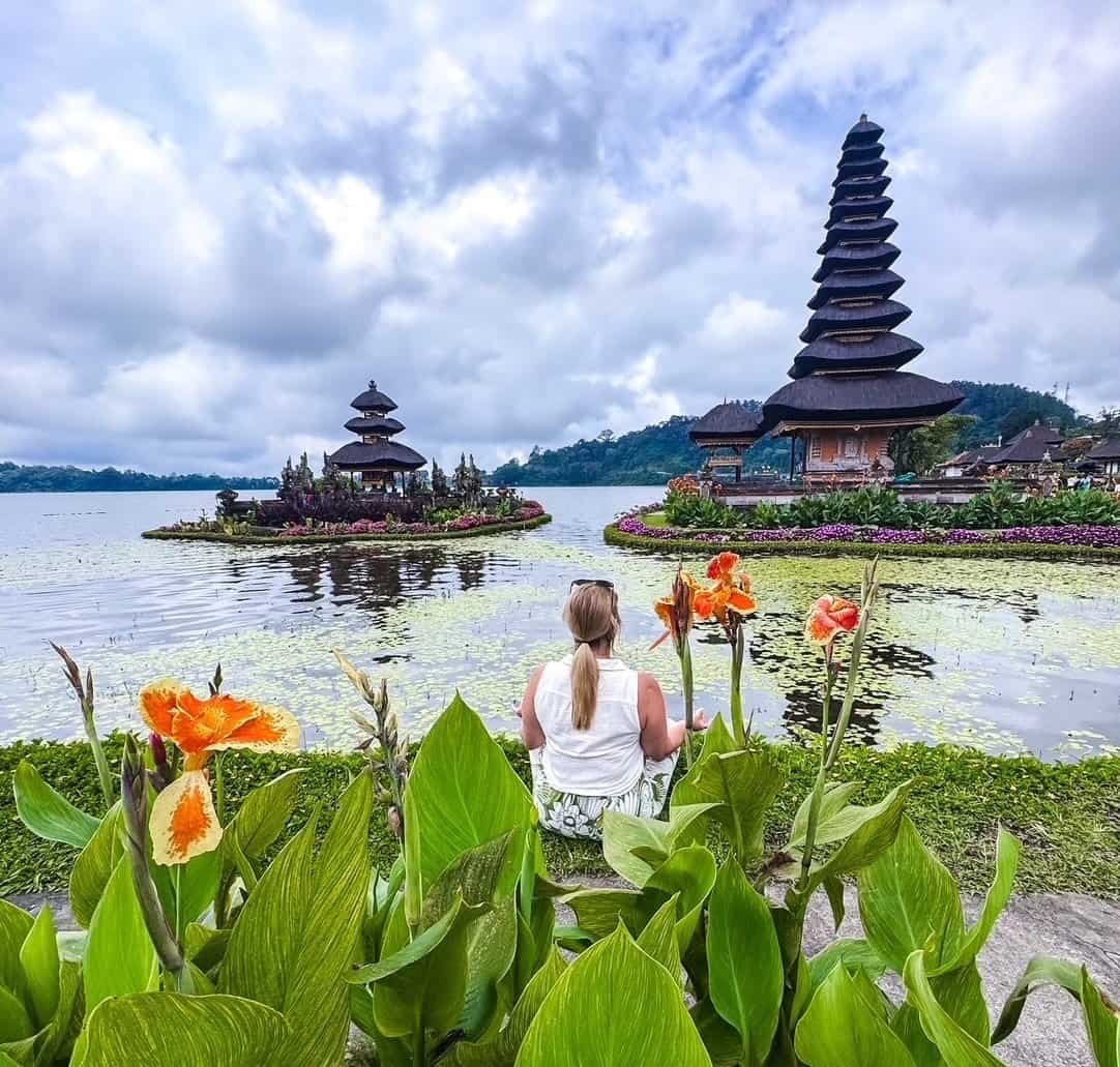 Charity seated by Lake Bratan facing the tiered shrines of the Ulun Danu Beratan water temple in Bali