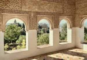 Ornate carved Moorish arches framing a view over Granada from the Alhambra, Spain