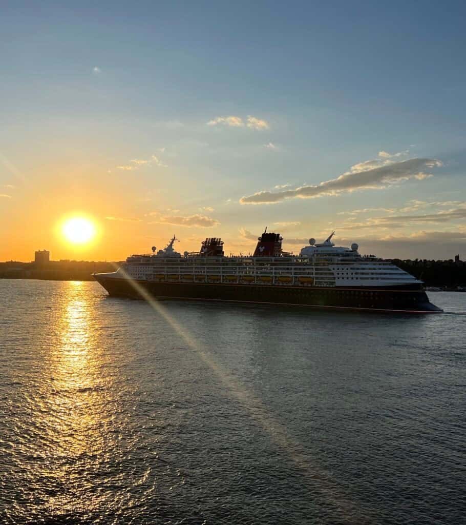 A Disney Cruise Line ship sailing into a golden sunset