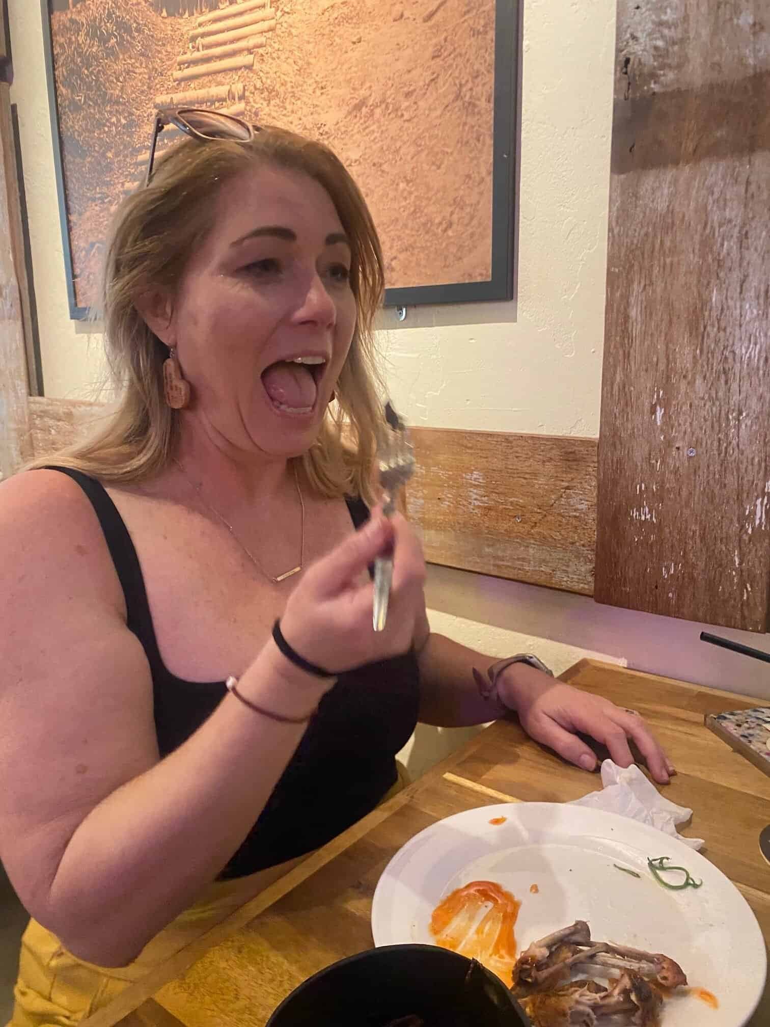 Travel advisor Charity Auger laughing with her mouth open as she prepares to eat a sago grub on a fork in Kuching, Borneo.