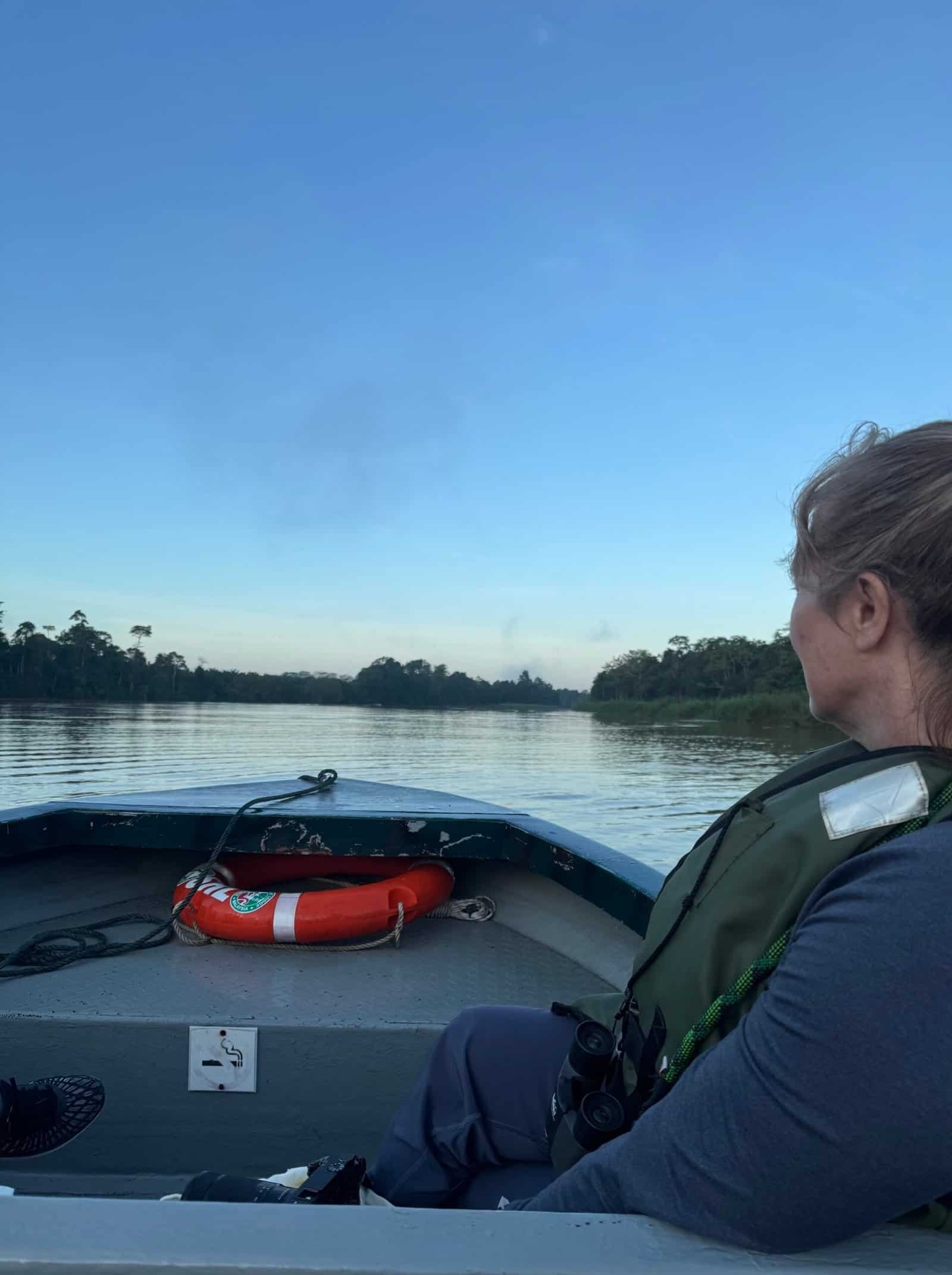 Charity Auger watching the quiet Kinabatangan River from a small boat at first light in Borneo.