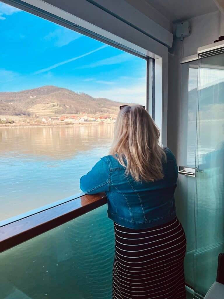 Charity gazing out a river cruise window at a hillside village in the Wachau Valley, Austria